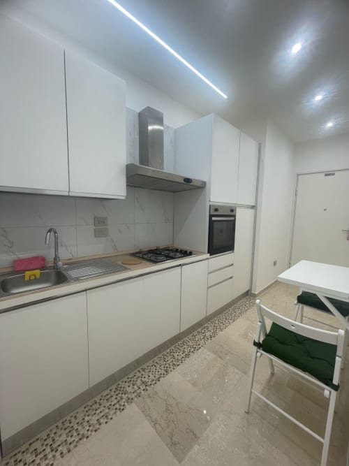 Cucina bianca moderna con piano cottura a gas, forno e zona pranzo nell'appartamento Dream Suite Bologna