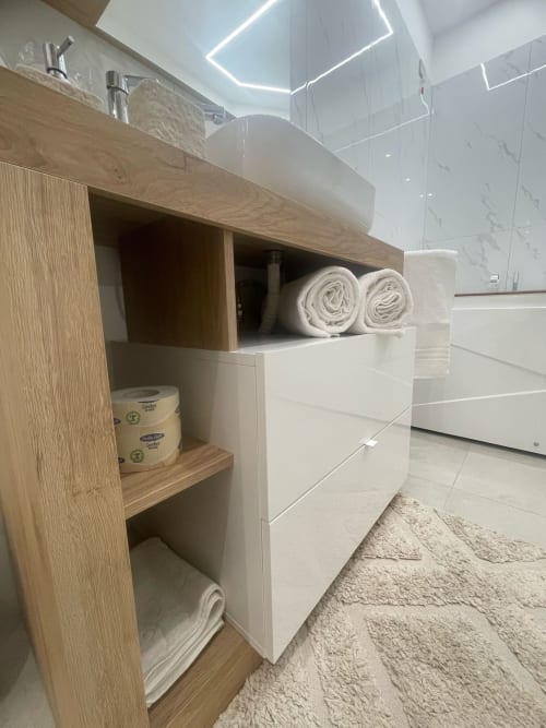 Vanità moderna del bagno con lavabo bianco a coppa, asciugamani arrotolati e scaffali di legno nella Dream Suite Bologna