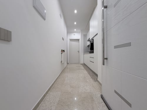 Elegante corridoio cucina con cabinetry bianca, elettrodomestici moderni e pavimento in marmo presso Dream Suite Bologna.