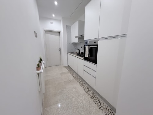 Cucina moderna bianca con elettrodomestici in acciaio inox nella suite Dream di Bologna, con mobili eleganti e marmo