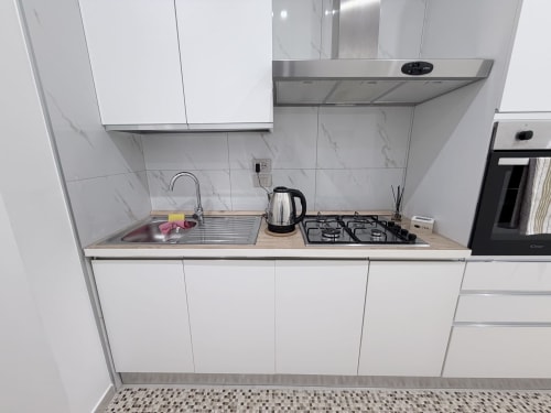 Cucina moderna bianca con alzatile in marmo, piano cottura a gas, lavello e cappa in acciaio inox nella Dream Suite Bologna