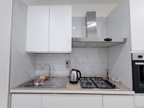 Cucina moderna nell'appartamento Dream Suite Bologna con armadi bianchi, alzata in marmo, piano cottura a gas, lavello e acciaio inox
