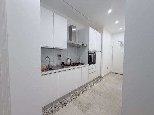 Cucina moderna nella Dream Suite Bologna con armadi bianchi, rivestimento in marmo, elettrodomestici in acciaio inox, e
