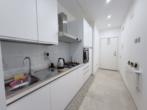 Cucina moderna bianca nella Dream Suite di Bologna con rivestimento in marmo, elettrodomestici in acciaio inox e corridoio di accesso