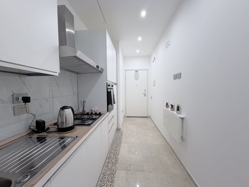 Cucina moderna nella suite Dream di Bologna con mobili bianchi, elettrodomestici in acciaio inox e pavimentazione in marmo