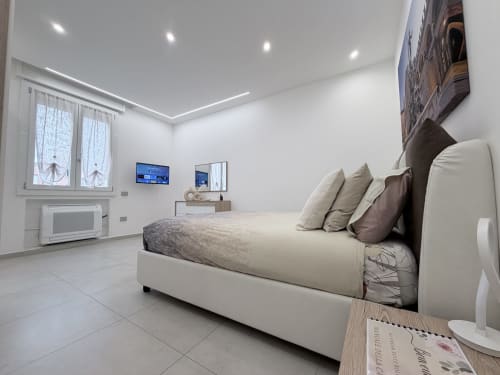 Camera moderna di Dream Suite Bologna con letto bianco, TV a schermo piatto e illuminazione brillante nell'appartamento King Deluxe
