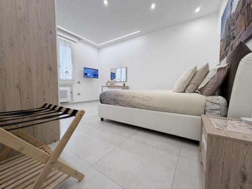 Camera da letto moderna King Deluxe presso Dream Suite Bologna con letto bianco, dettagli in legno e design minimalista