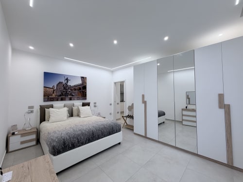 Camera da letto King Deluxe moderno presso Dream Suite Bologna con guardaroba specchiato, letto grigio e pavimentazione in marmo