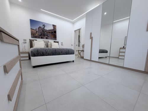 Moderna camera da letto con armadi specchiati, letto bianco e pavimento in marmo presso Dream Suite Bologna