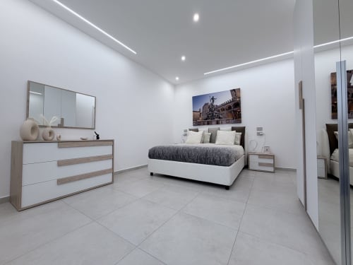 Camera da letto moderna della Dream Suite Bologna con letto king, cassettone bianco, specchio e foto della città in appartamento Deluxe minimalista.