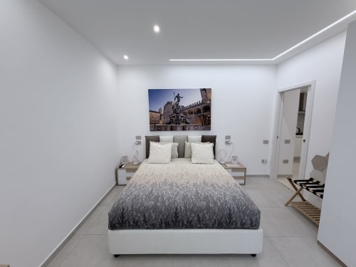 Camera King Deluxe moderna della Dream Suite Bologna con biancheria grigia, pareti bianche, illuminazione contemporanea e vista di Bologna