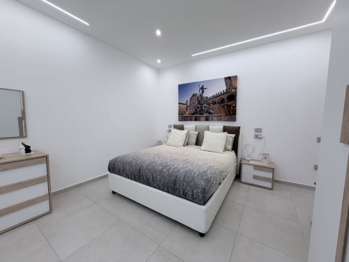 Camera moderna Dream Suite Bologna con letto king size, biancheria grigia, comodini in legno e opere d'arte di architettura italiana