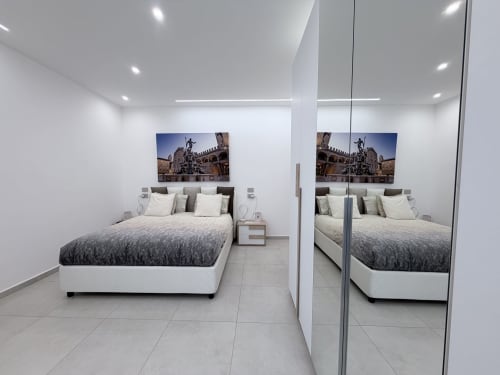 Camera moderna nella Dream Suite Bologna con letto king, armadio specchiato e quadri con veduta della città in appartamento su cortile interno
