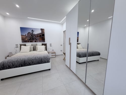 Camera da letto deluxe stile moderno presso Dream Suite Bologna con armadio a specchio, biancheria grigia e bianca, e arredamento italiano