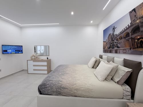 Appartamento deluxe Dream Suite Bologna: camera con letto, TV, cassettone e arte architettonica italiana in parete