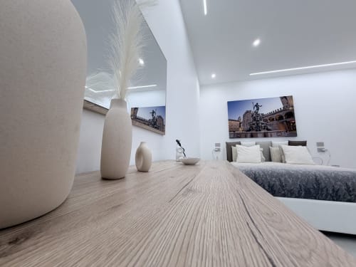 Camera moderna della Dream Suite Bologna con pavimento in legno chiaro, vasi in ceramica crema, letto con cuscini e opere d'arte con veduta cittadina