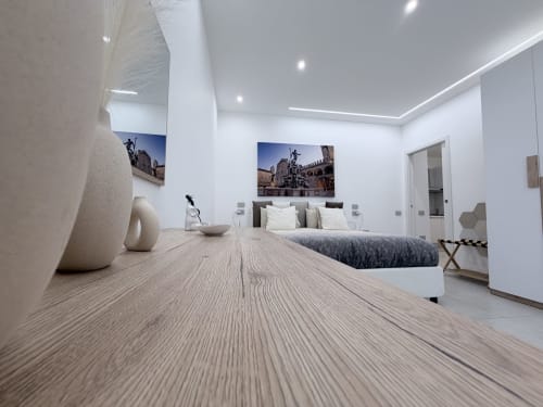 Camera da letto Modern King Deluxe presso Dream Suite Bologna con pavimenti in legno, pareti bianche e opere d'arte urbana