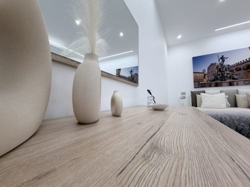 Camera moderna con vasi in ceramica color crema, pavimentazione in legno, letto con cuscini e opere d'arte urbana presso Dream Suite Bologna