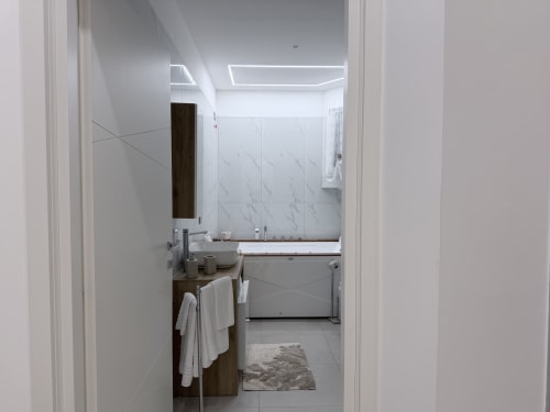 Bagno moderno della Dream Suite Bologna con piastrelle in marmo, lavabo, vasca e scaldasalviette riscaldato con asciugamani bianchi