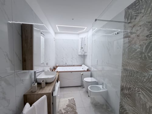 Bagno moderno con rivestimenti in marmo, scaldasalviette, lavabo bianco, wc, bidet e vasca idromassaggio all'Dream Suite Bologna