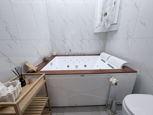 Vasca idromassaggio lussuosa con getti idroterapici e vassoio in legno nel bagno Dream Suite Bologna King Deluxe con rivestimenti in marmo