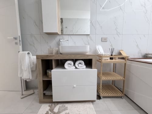 Bagno moderno nella Dream Suite Bologna con piastrelle in marmo, mobile in legno, lavabo bianco e ripiani con asciugamani