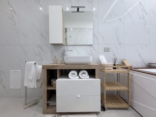 Bagno moderno della Dream Suite Bologna con piastrelle in marmo, mobile in legno, lavabo bianco e scaffali organizzati