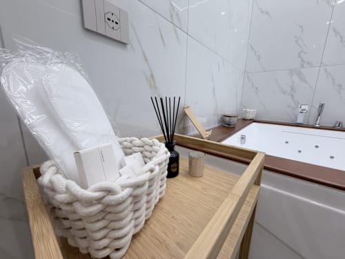 Lussuoso bagno della Dream Suite Bologna con piastrelle in marmo, dettagli in legno, vasca da bagno e cesto con amenities spa