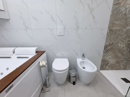 Bagno moderno nella suite Dream di Bologna con rivestimenti in marmo bianco, toilet, bidet e lavabo