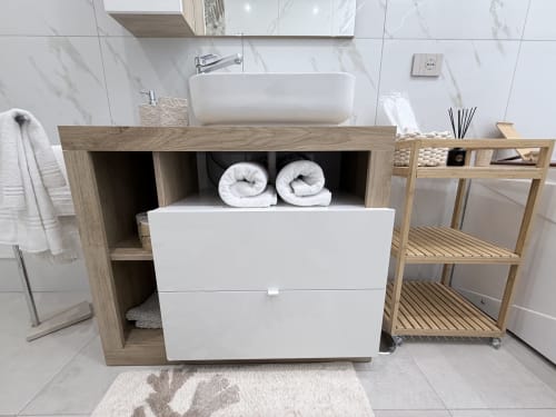Vanity bagno moderno con lavabo in ceramica bianca, mobile in legno, asciugamani arrotolati e piastrelle in marmo alla Dream Suite