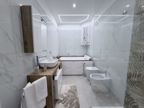 Bagno moderno nella Dream Suite Bologna con piastrelle di marmo, mobile in legno, vasca idromassaggio, bidet e scaldarottoli