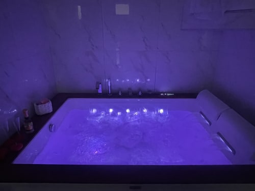 Vasca idromassaggio illuminata con luci viola nel bagno della suite Dream Suite Bologna King Deluxe