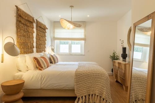 Coastal bedroom at Sea'Ya Villas in Cascais with natural woven decor, white bedding, and warm lighting