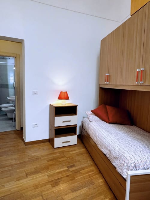 Camera da letto moderna nell'appartamento WelcHome a Lanciano con letto in legno, comodino, lampada arancione e armadio a muro