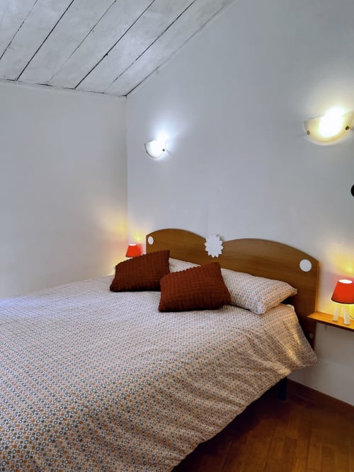Accogliente camera da letto a WelcHome a Lanciano con letto in legno, cuscini marrone, biancheria fantasia e illuminazione calda