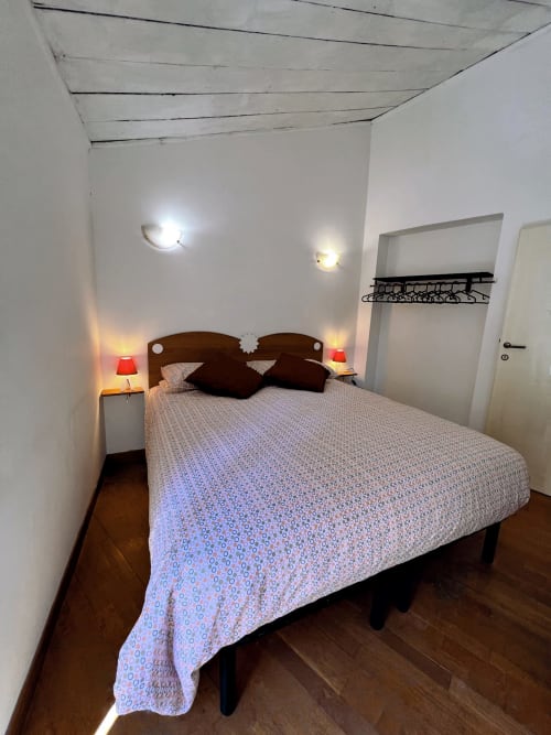 Camera accogliente nell'appartamento Nel Cuore di Lanciano con letto matrimoniale, testiera marrone, lampade da comodino e soffitto bianco