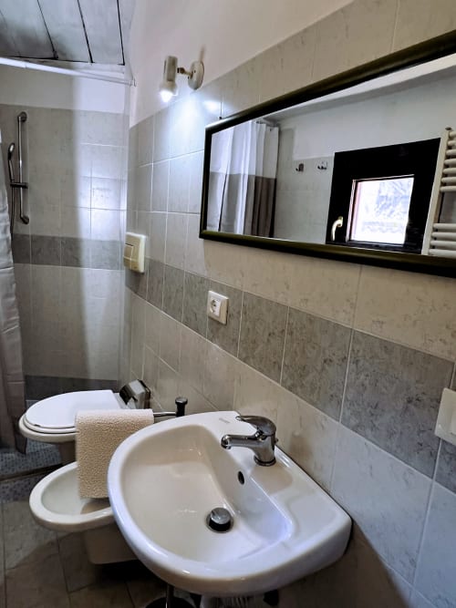 Bagno moderno nell'appartamento WelcHome, Lanciano. Lavabo bianco, wc, specchio incorniciato, pareti piastrellate, doccia e portasciugamani