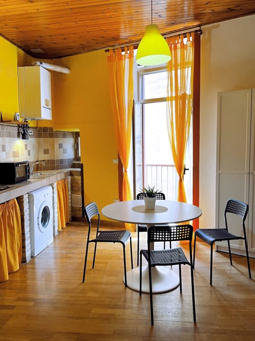 Luminosa zona cucina-pranzo in WelcHome apartment a Lanciano con tavolo rotondo bianco, sedie nere e elettrodomestici moderni