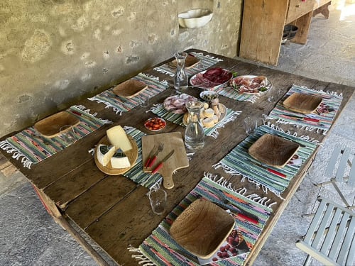 Rustic outdoor dining setup at Roseto del Drago with wooden table, traditional striped runners, and Mediterranean appetizers