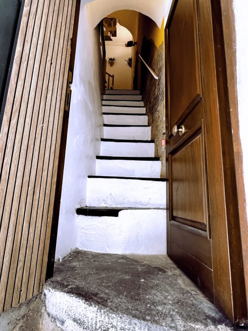 Scala stretta con pareti bianche e gradini bordati di nero che conduce verso l'alto presso l'appartamento WelcHome a Lanciano, Italia