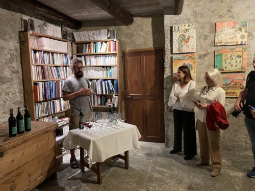 Wine tasting event at Roseto del Drago B&B in Ponte In Valtellina, guests gathered in rustic cellar with bookshelves