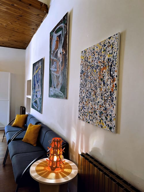 Elegante zona living con divano blu, cuscini gialli, opere d'arte astratta su pareti bianche e lampada sculptorea arancione