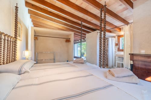 Amplio dormitorio de villa en Can Mantellé, Artà, con vigas de madera vista, camas gemelas y comodidades modernas