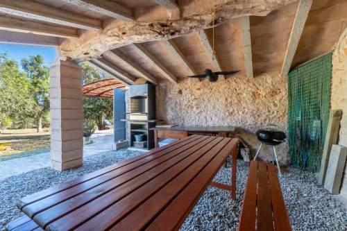 Terraza cubierta con banco de madera y barbacoa en la villa Can Mantellé en Artà, España