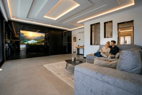Sala moderna en Villa La Menta, Gran Canaria con sofás grises, televisor e iluminación elegante en el techo