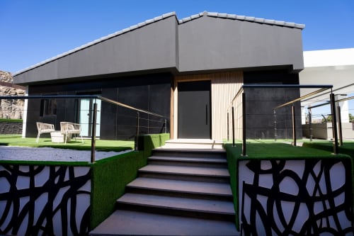 Entrada de villa moderna en Home Stay Gran Canaria con arquitectura minimalista negra, jardín bien cuidado y terraza