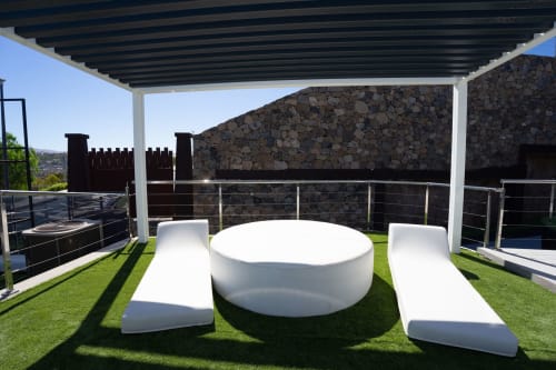 Moderna zona de descanso blanca y redonda sobre césped artificial con muro de piedra y pérgola en Villa La Menta, Gran Canaria
