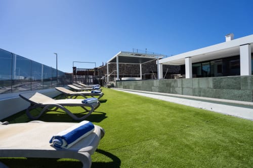 Terraza de lujo con tumbonas, jardín cuidado, arquitectura moderna y piscina en Home Stay Gran Canaria, Las Palmas