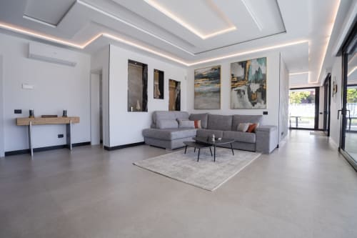 Sala de estar de villa moderna con sofá sectional gris, obras de arte y vistas a la piscina en Home Stay Gran Canaria, Las Palmas