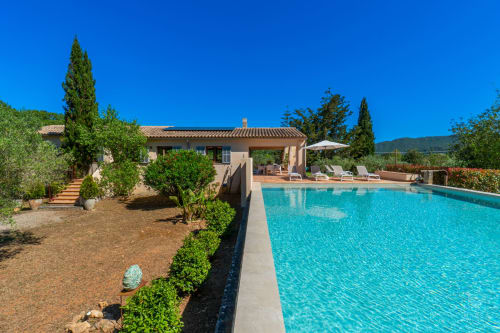 Villa de lujo en Artà con piscina turquesa, tumbonas y jardines mediterráneos bajo cielo azul